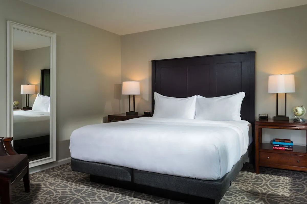 A cozy and serene bedroom featuring a plush bed, mirrored wardrobe, and bedside tables with soft-glow lamps. The space is inviting, perfect for unwinding after a day of adventure or romantic activities, and suggests comfort and relaxation with its soft blankets and ambient lighting.